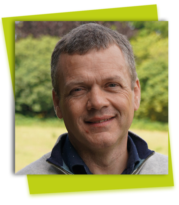 Smiling man outdoors in front of a blurred green background, framed by a lime-green border.