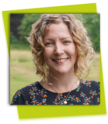 Smiling woman with curly blonde hair in a floral top, outdoors against a blurred green background.