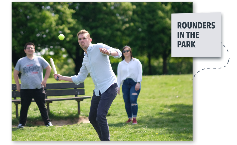 People playing rounders in a sunny park, with one person throwing a ball.