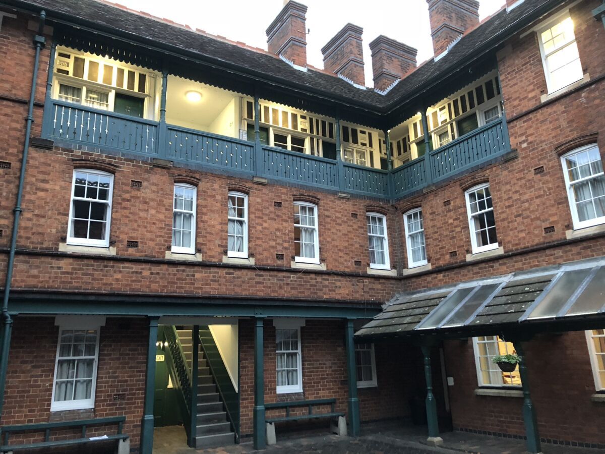 Brick courtyard of a multi-story building with lit windows and staircases around an open central area