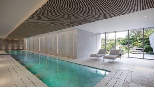Indoor lap pool with turquoise water, lounge chairs, and floor-to-ceiling windows overlooking greenery