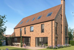 Modern brick house with steep roof, skylights, and a small patio in a sunny yard