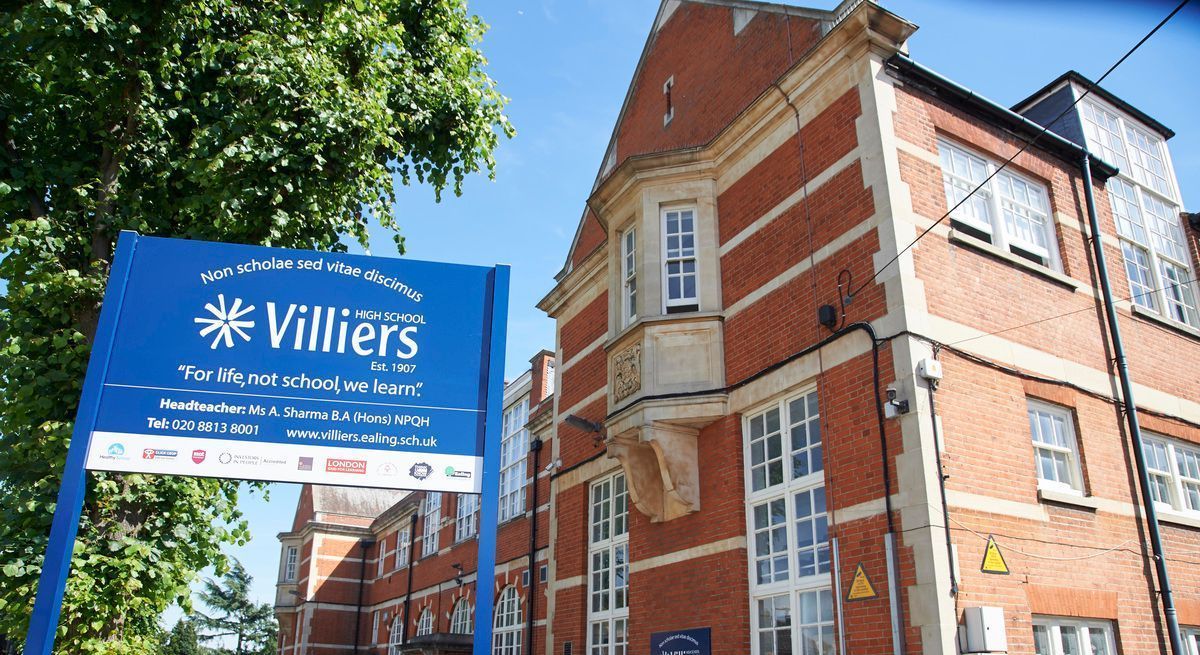 Blue Villiers sign beside a red-brick building under a sunny sky