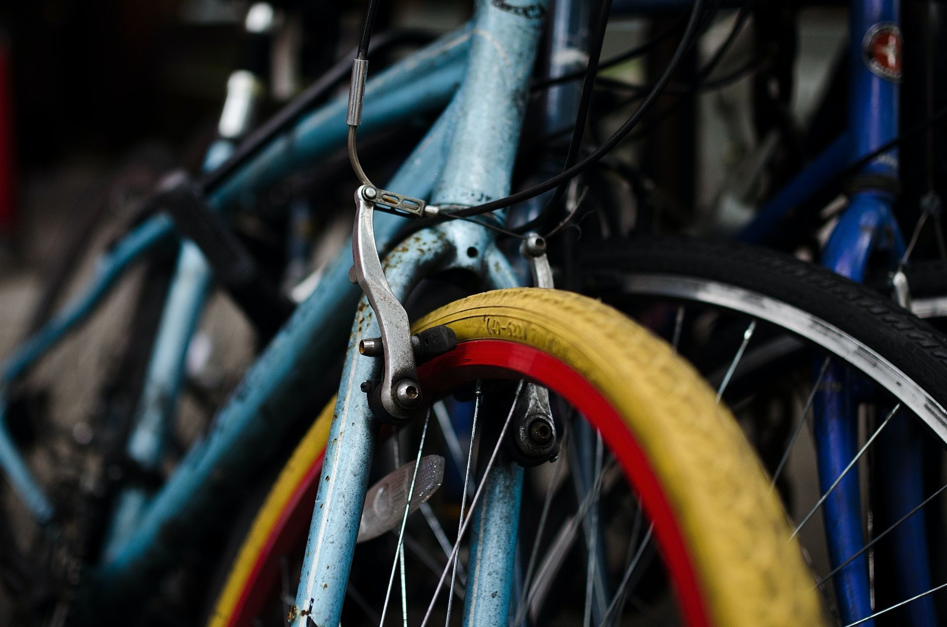 Bicycles packed closely together, with a yellow and red front wheel in the foreground.