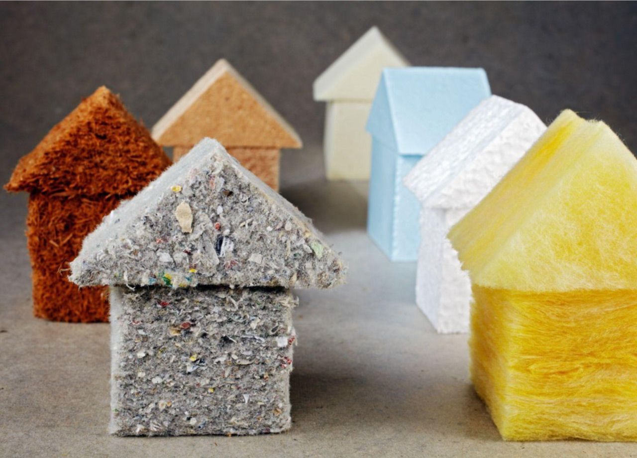 Small house-shaped samples made of colorful recycled material on a gray surface.