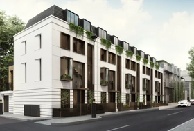 Modern white apartment building with dark balconies along a city street