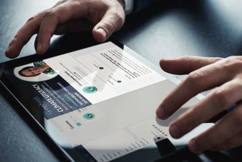 Hands using a tablet to browse a white dashboard interface with charts and profile details