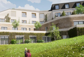 Modern apartment building with balconies and a grassy hillside in front
