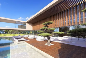 Modern resort poolside deck with lounge chairs, reflecting pool, and wooden architectural building under a blue sky