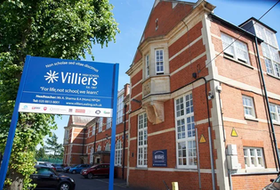 Villiers School entrance sign beside a red-brick school building on a sunny day