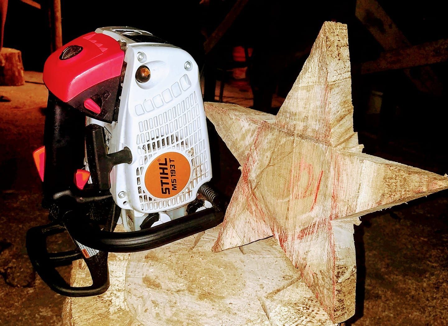 Red and white electric cutter beside a carved wooden star on a workbench.