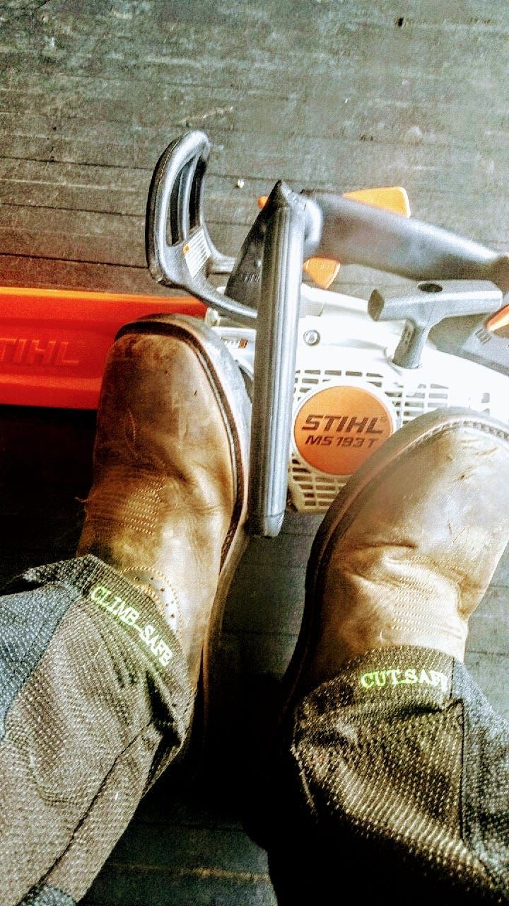 Work boots standing beside a circular saw and a tape measure on a concrete floor