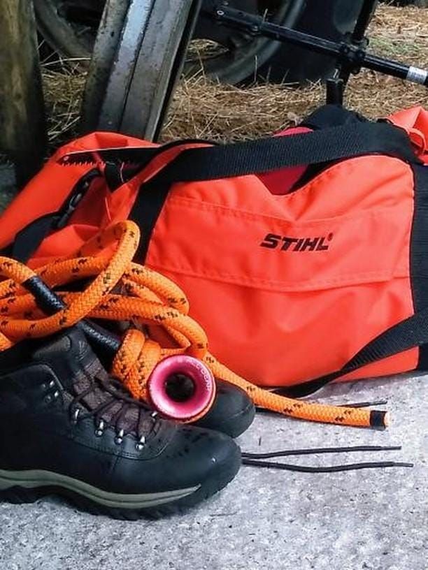 Orange STIHL bag beside black hiking boot and orange rope on a concrete floor.