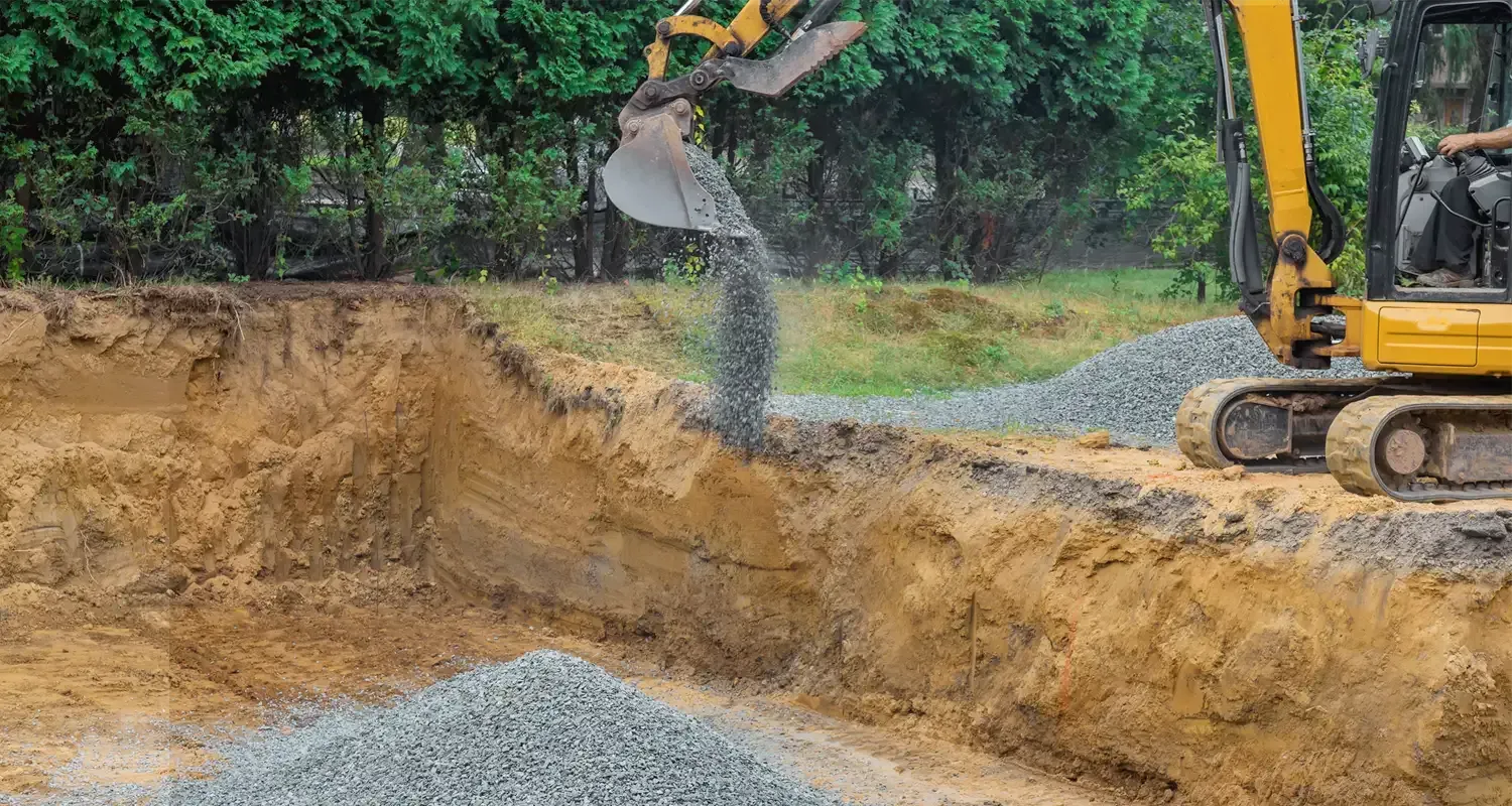A yellow excavator is digging a hole in the ground.