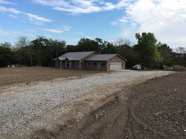 A house is sitting in the middle of a gravel road