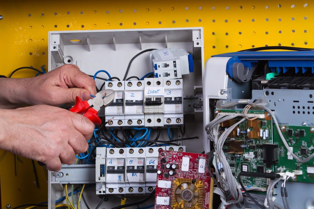 A Man is Working on an Electrical Box With a Screwdriver — Sigley Electrical in Tweed Heads, NSW