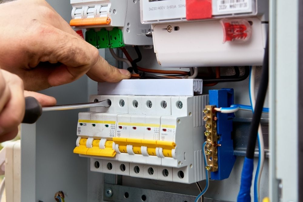 A Person is Working on an Electrical Box With a Screwdriver — Sigley Electrical in Byron Bay, NSW