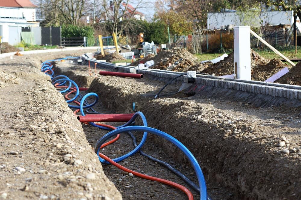 A Bunch of Electrical Wires Are Laying in the Dirt on a Construction Site — Sigley Electrical in Mullumbimby, NSW
