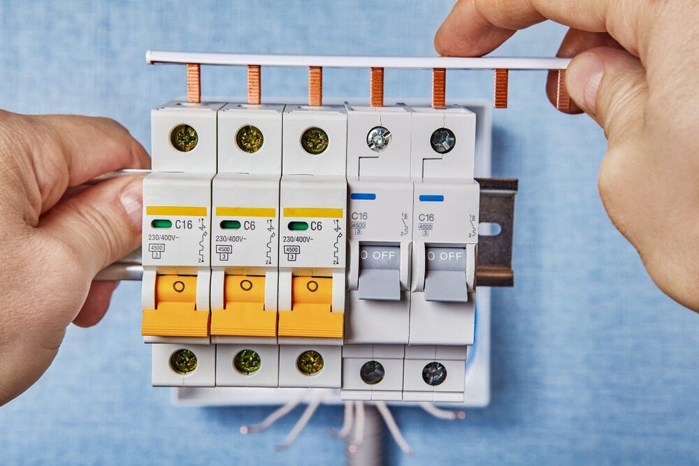 A Person is Installing a Circuit Breaker on a Wall — Sigley Electrical in Tweed Heads, NSW