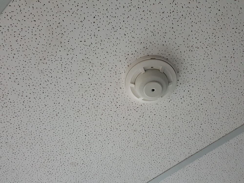 A Smoke Detector is Mounted to the Ceiling of a Room — Sigley Electrical in Byron Bay, NSW