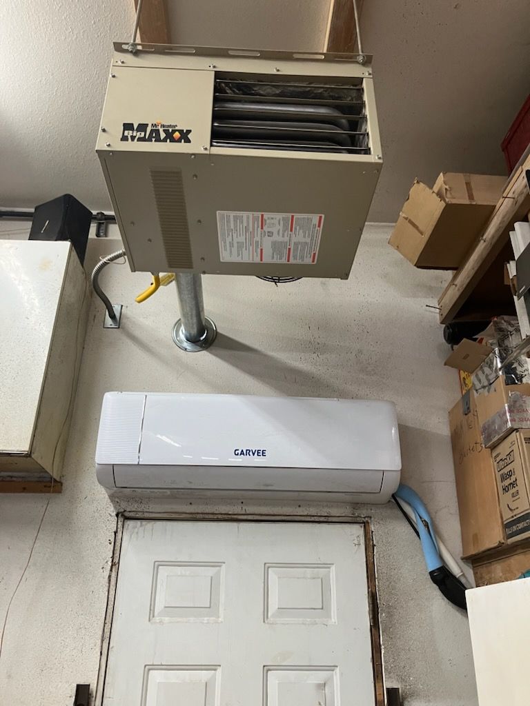Basement utility area with HVAC unit above a white door and a portable AC near storage boxes