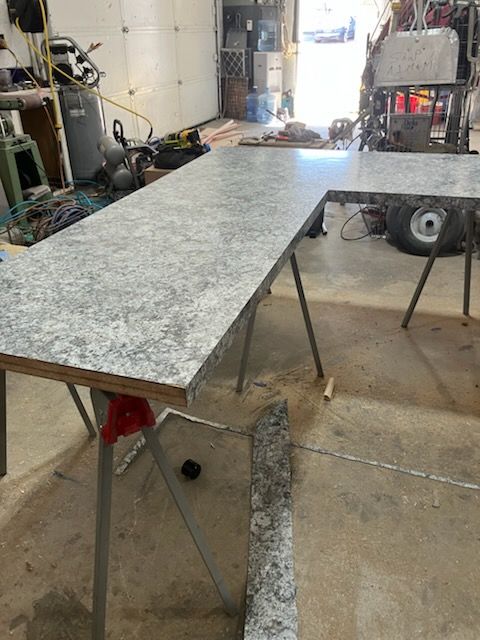 Granite countertop slab on folding sawhorses in a workshop garage