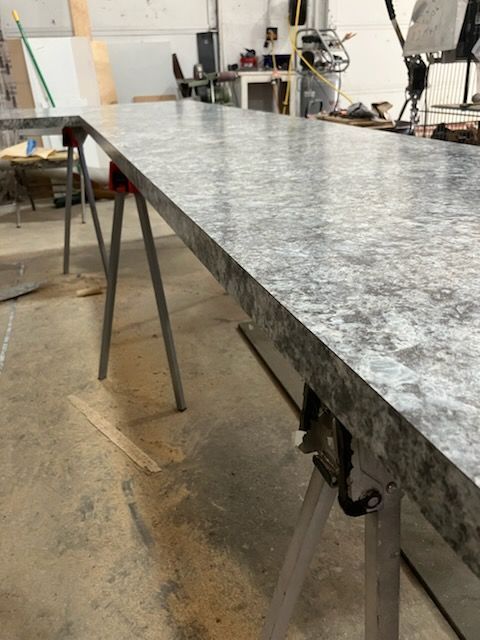 Marble-pattern countertop slab on saw horses in a workshop