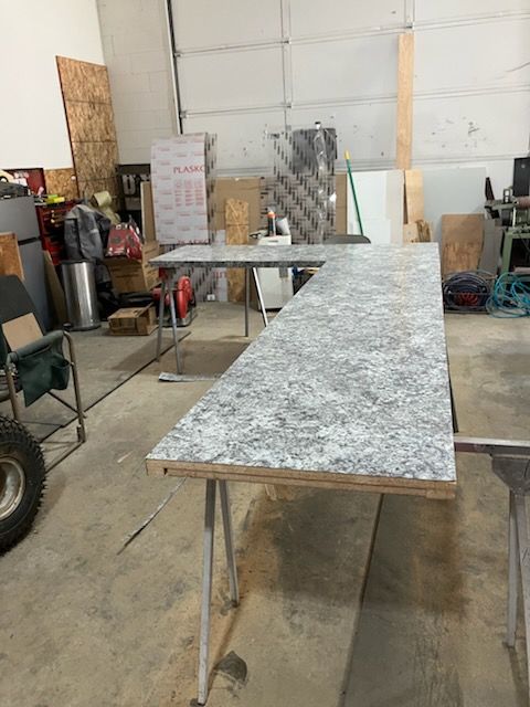 Workshop with a long speckled countertop on metal legs, surrounded by tools and materials.