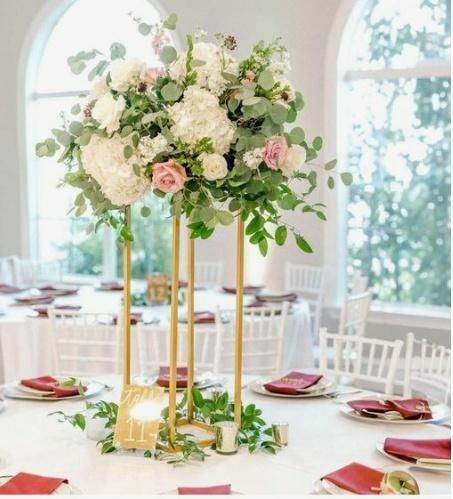 Gold floral centerpiece with white and pink flowers on a round table set for a formal event.