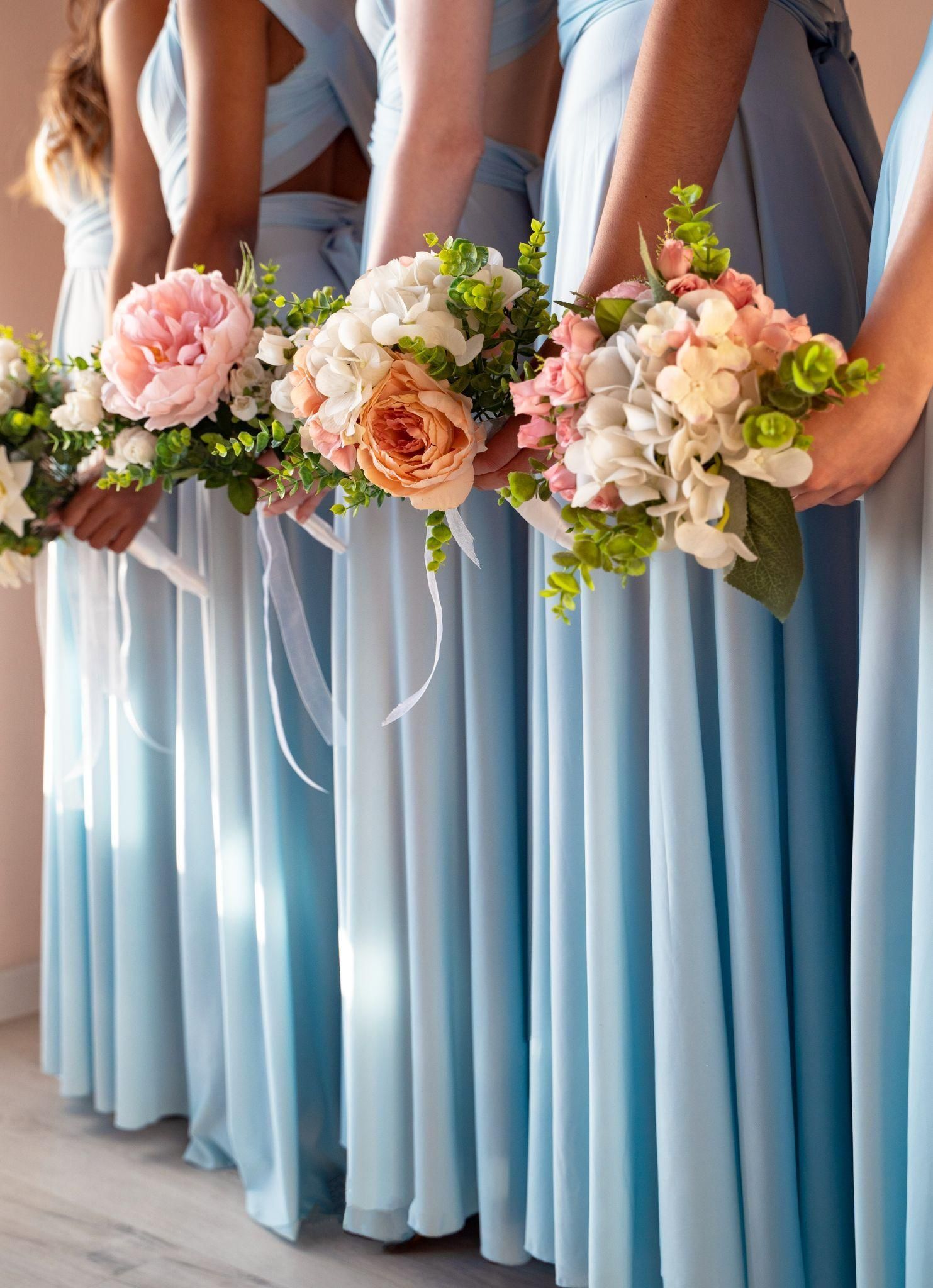 Bridesmaids in light blue dresses holding bouquets of flowers.