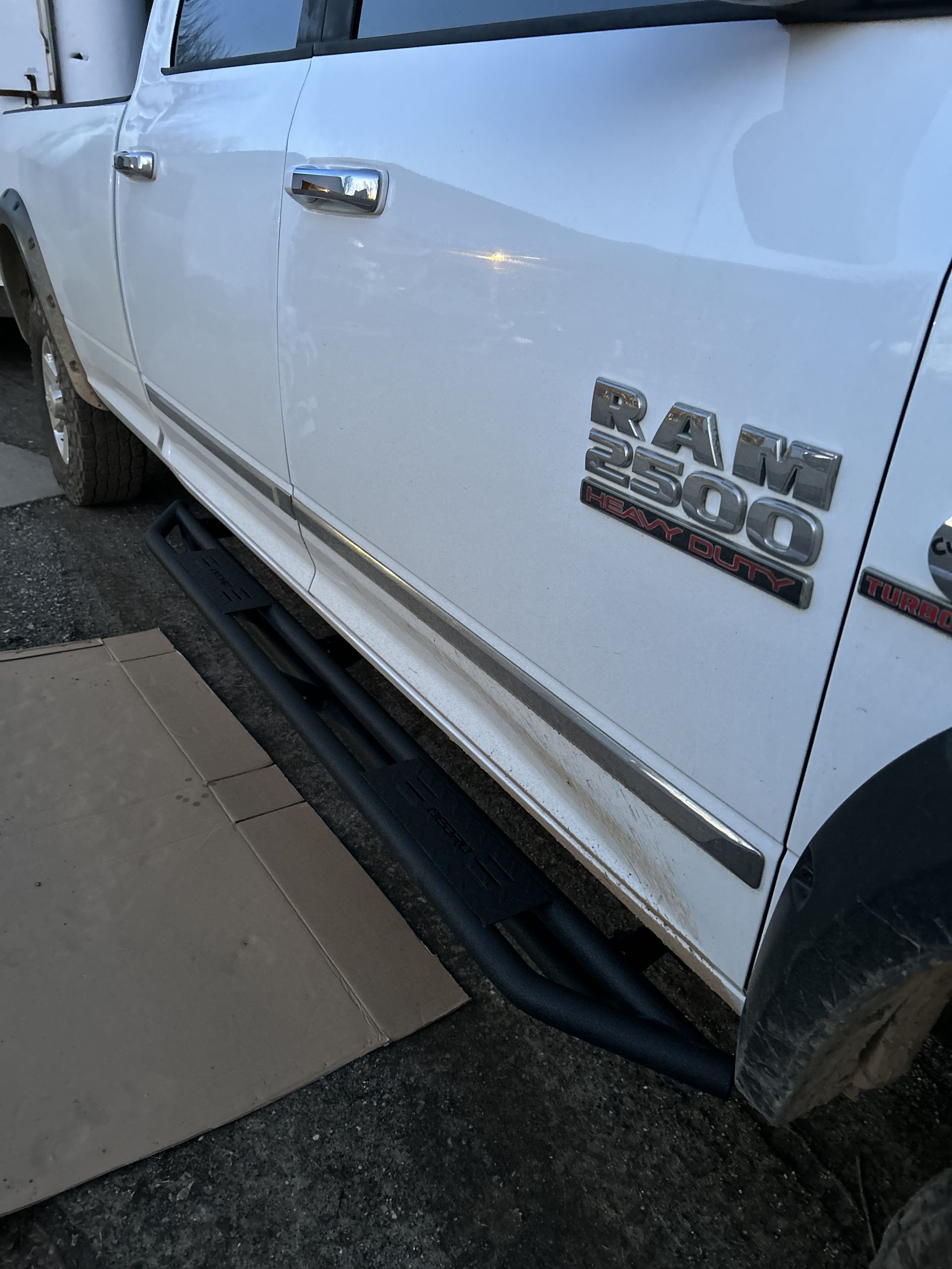 White RAM 1500 pickup truck parked by a curb, side view with running board visible.