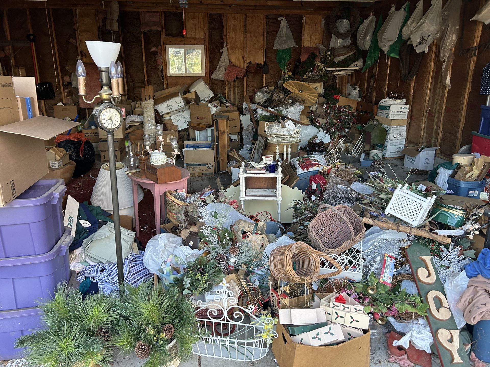 Cluttered garage packed with boxes, lamps, decorations, and assorted household items