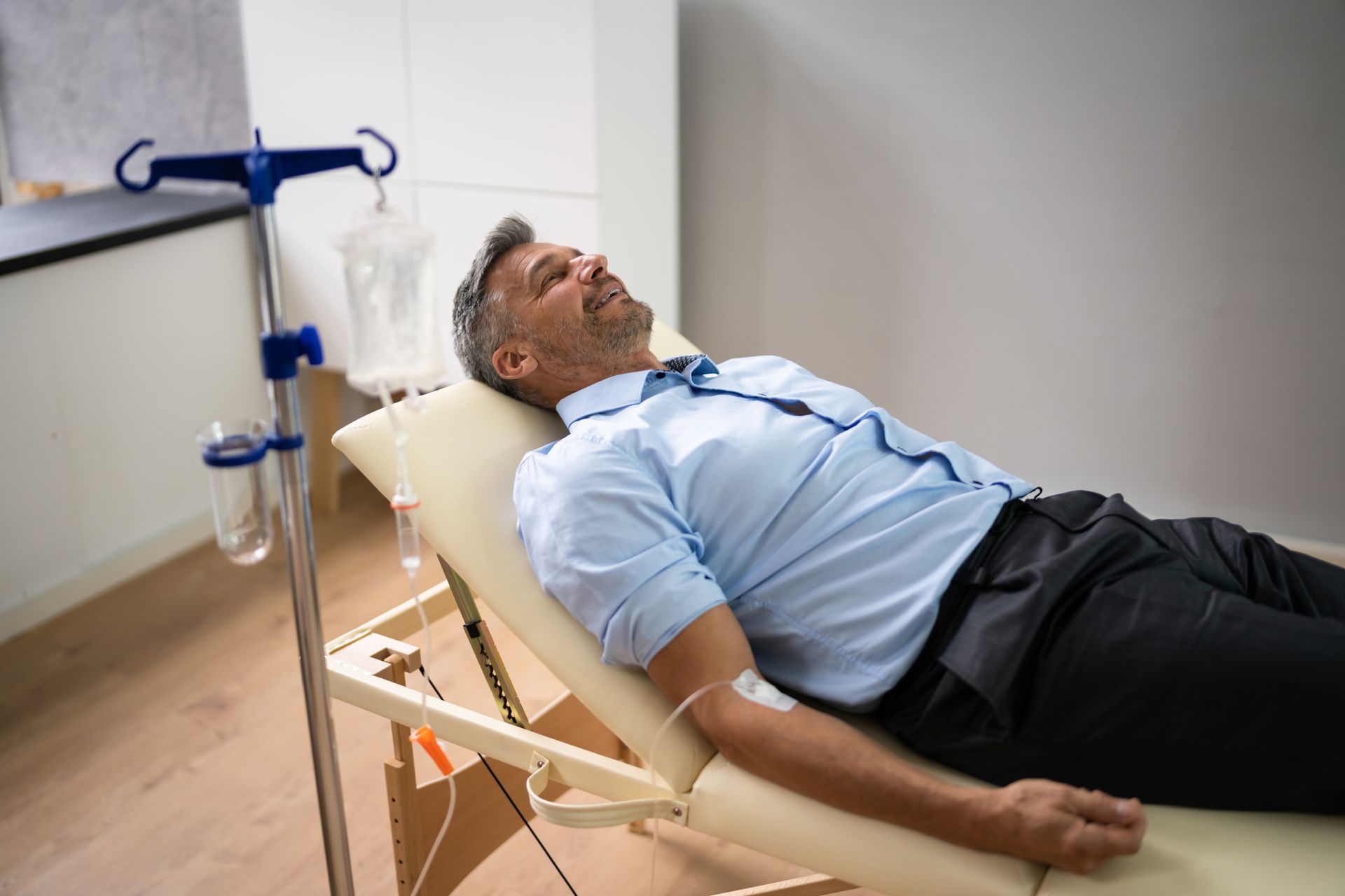 A man is laying in a hospital bed with an iv in his arm.
