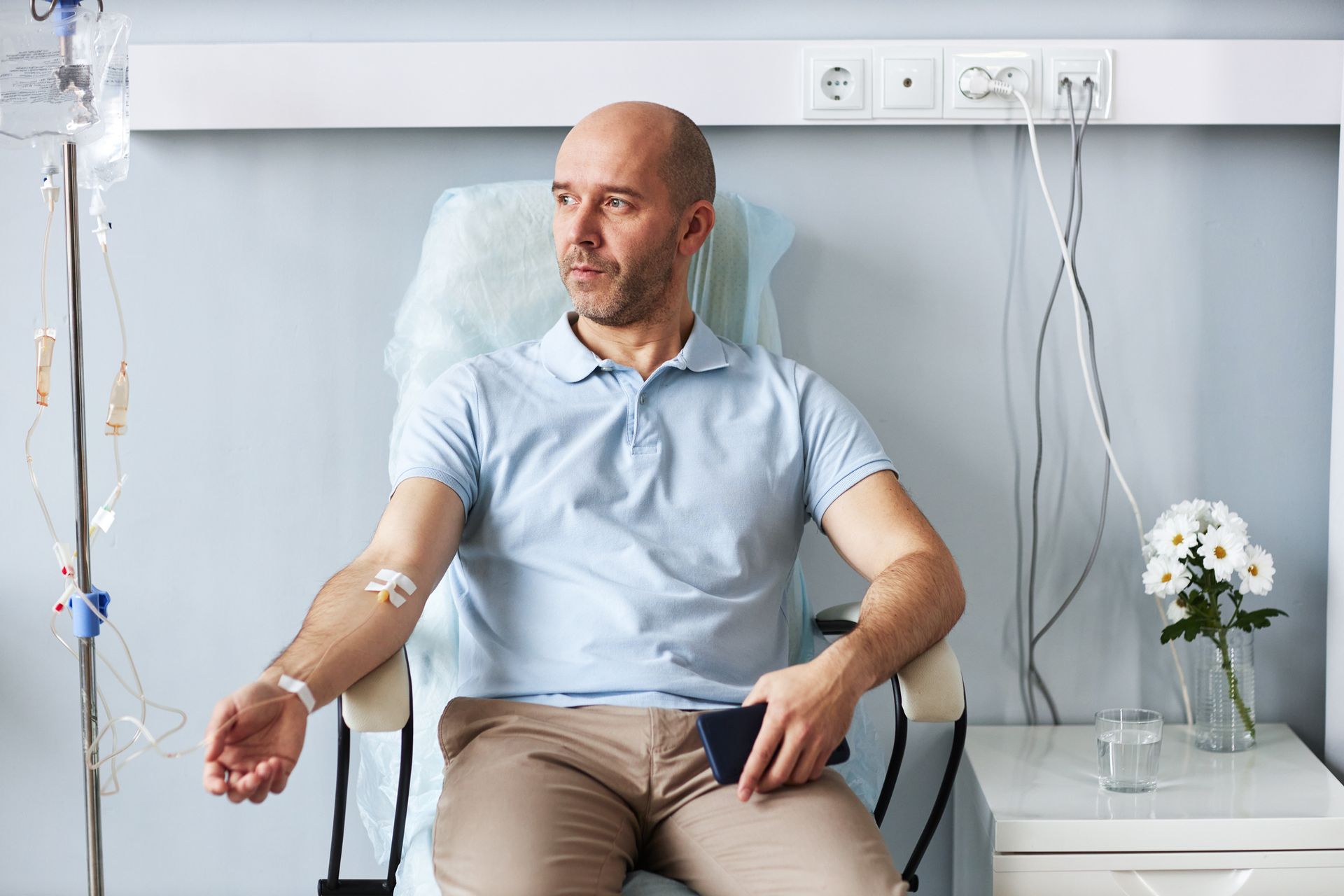 A man is sitting in a hospital chair with an iv in his arm.