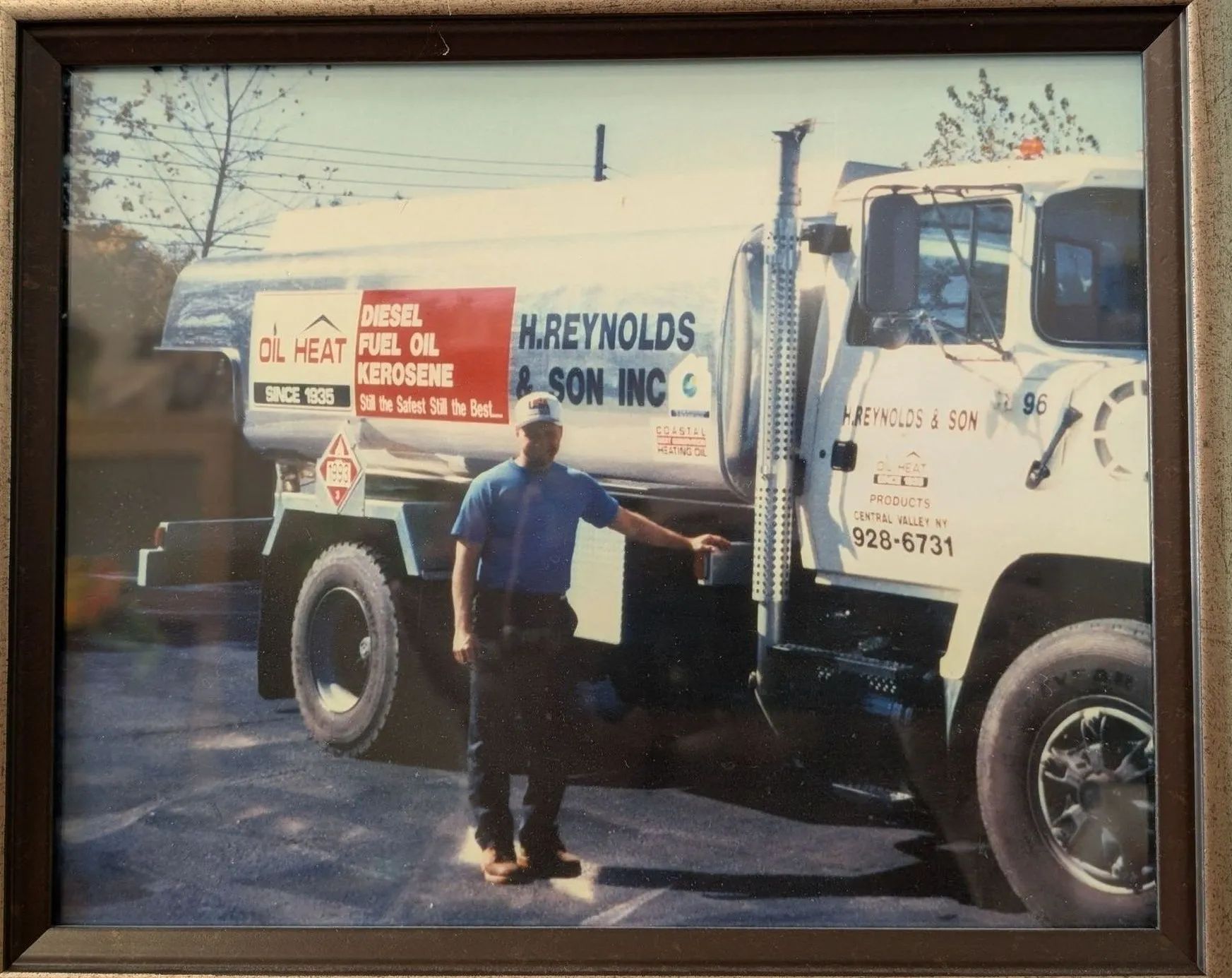 Man standing by two utility trucks with company logos and service signs in a parking lot