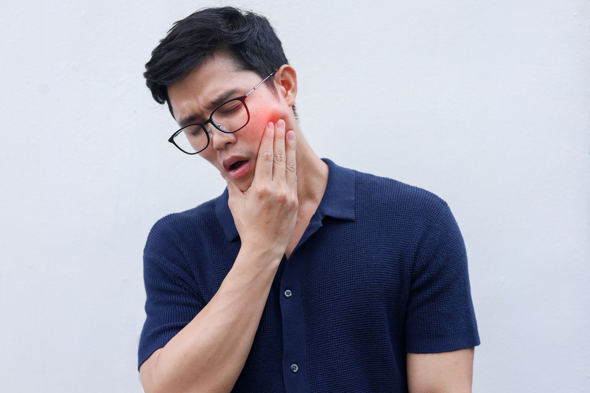 Man wearing glasses holding his jaw in discomfort, illustrating TMJ pain linked to nasal breathing