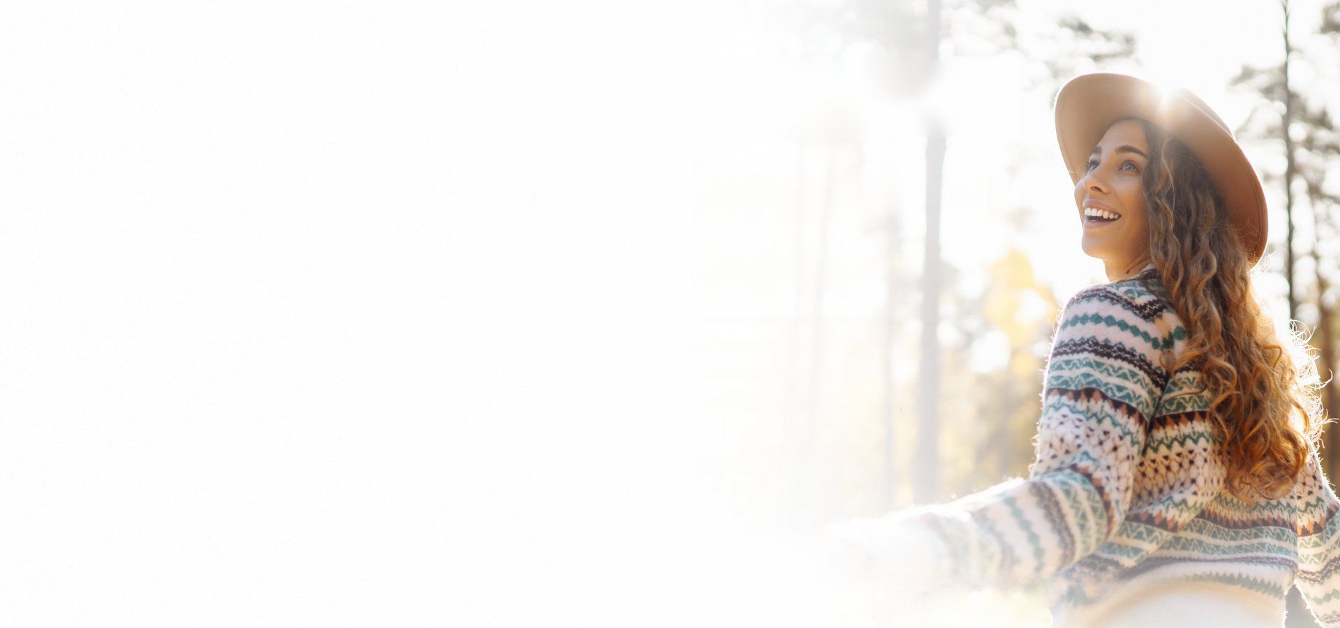 Smiling woman in a sweater and hat enjoying fresh air outdoors
