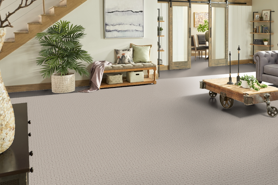 Neutral carpeted room with rustic furniture and accents, including a bench and a coffee table.