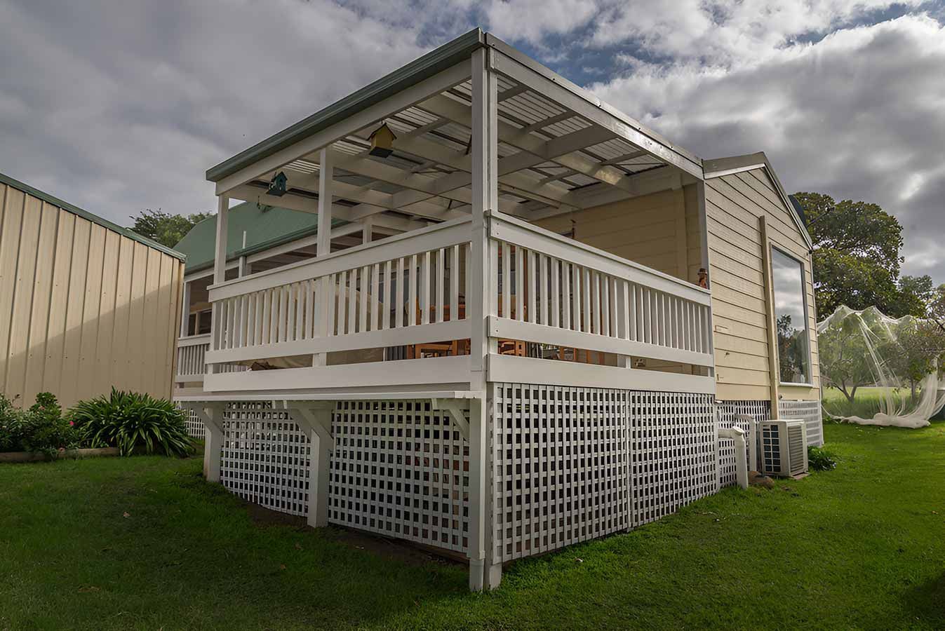 A Small House With a Porch and a White Railing — 2 Deadly Timber & Lattice in Charters Towers, QLD