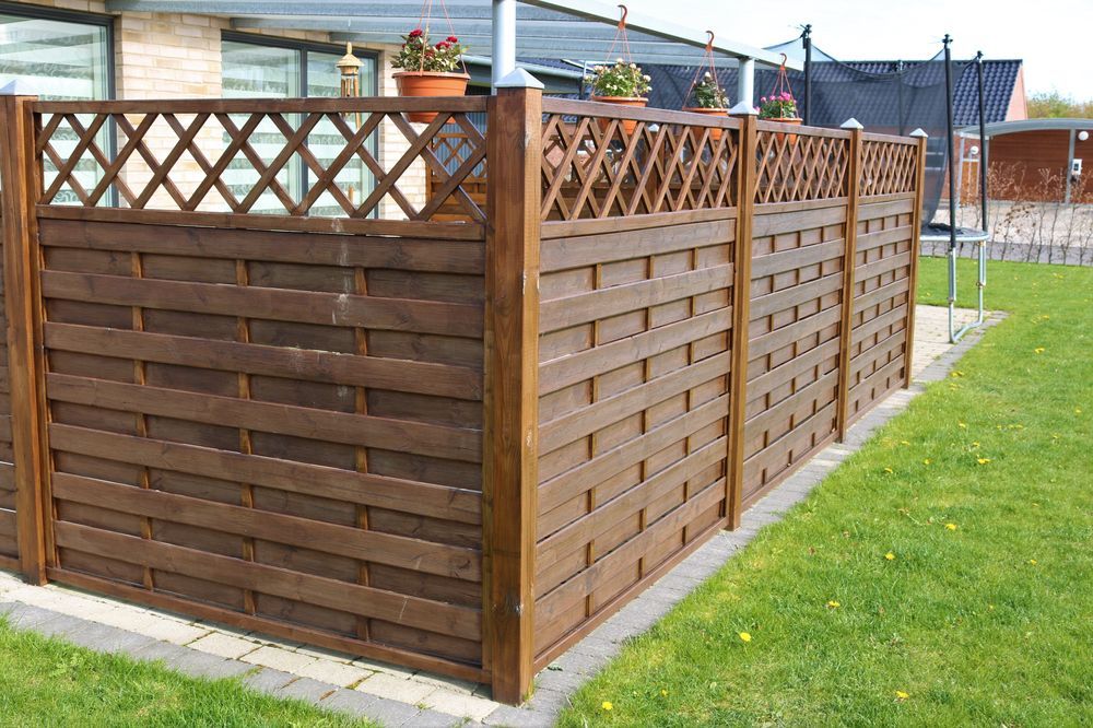 A Man is Painting a Wooden Fence in Front of a House — 2 Deadly Timber & Lattice in Ayr, QLD