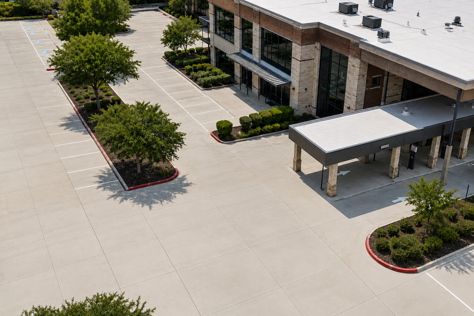 Aerial view of a building entrance with trees, sidewalks, and a covered drop-off area.