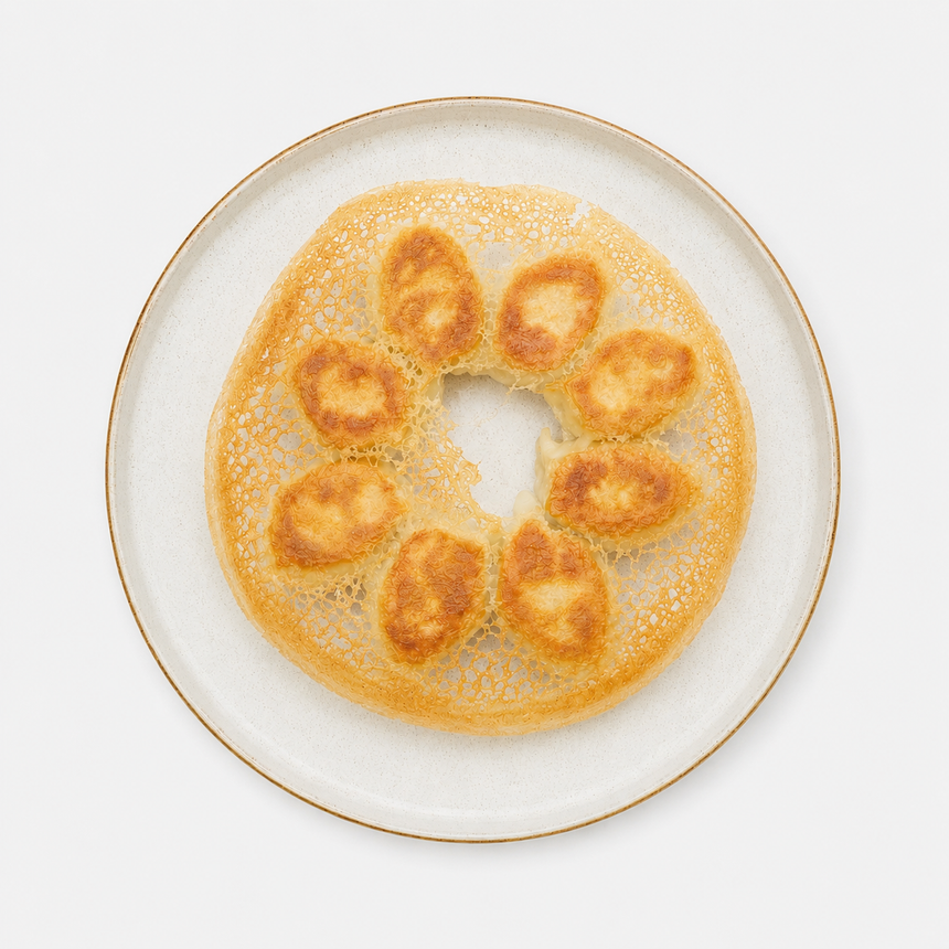 White plate with a ring of golden, fried dough pieces around the center on a plain background