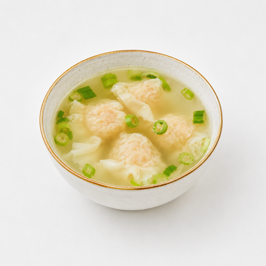 Bowl of clear soup with dumplings and chopped green onions on a white background