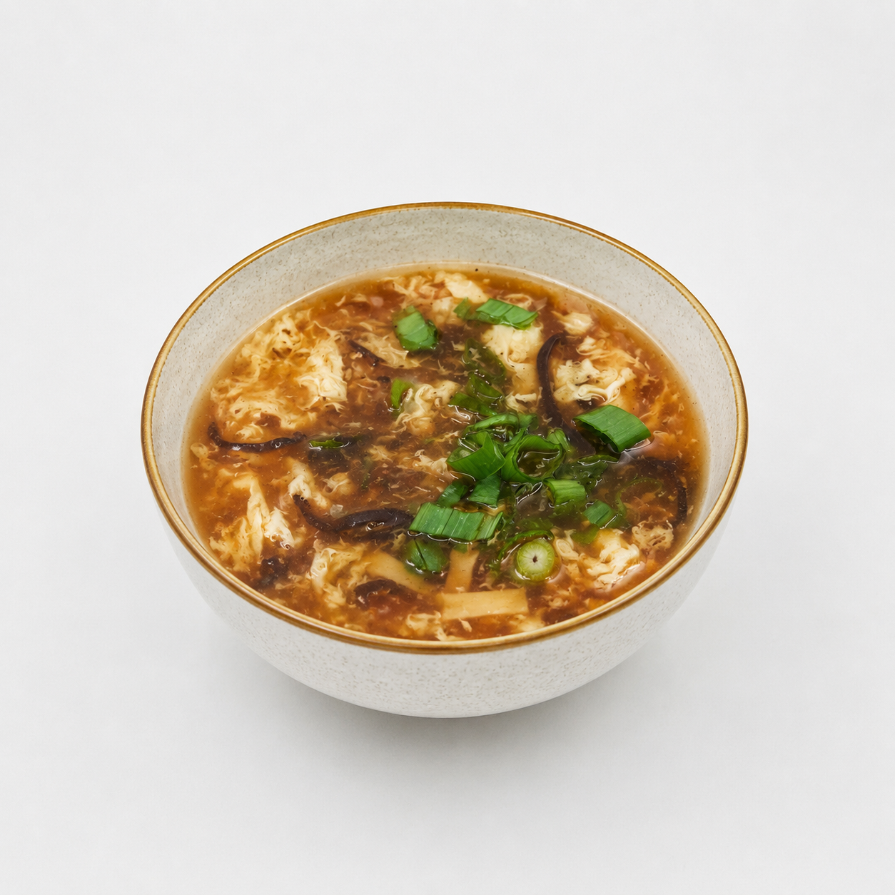 A bowl of noodle soup topped with herbs and sliced mushrooms on a white background
