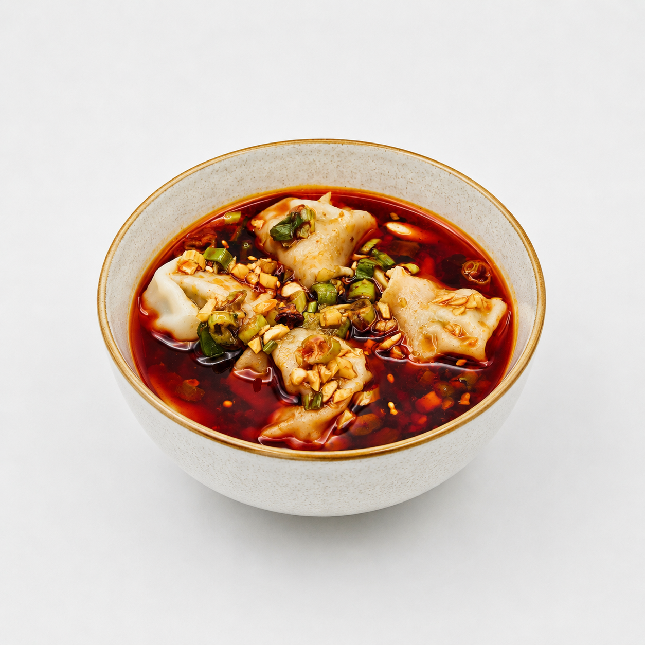 Bowl of red soup with dumplings and chopped green garnish