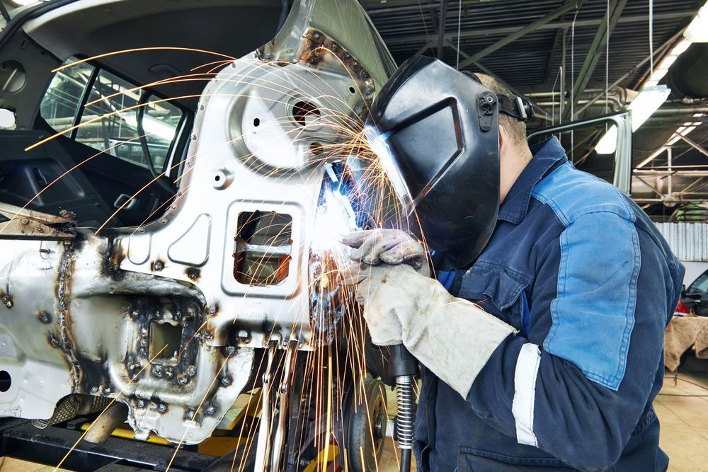 A Man Wearing a Welding Mask is Welding a Car in a Factory — Outlaw Mechanical & Performance In Inverell, NSW