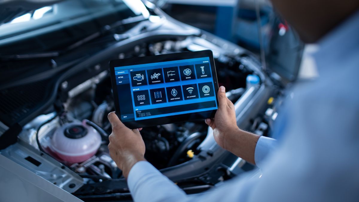 A Man is Holding a Tablet in Front of a Car Engine — Outlaw Mechanical & Performance In Inverell, NSW