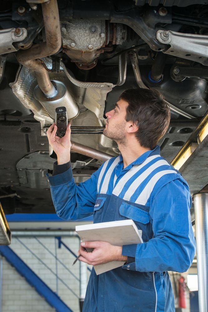 A Mechanic is Looking Under a Car — Outlaw Mechanical & Performance In Inverell, NSW