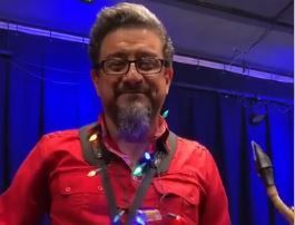 A man with a beard and glasses is wearing a red shirt.