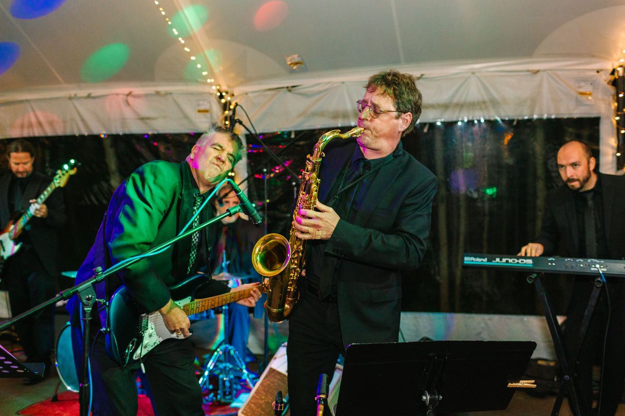 A man is playing a saxophone in a band on stage.